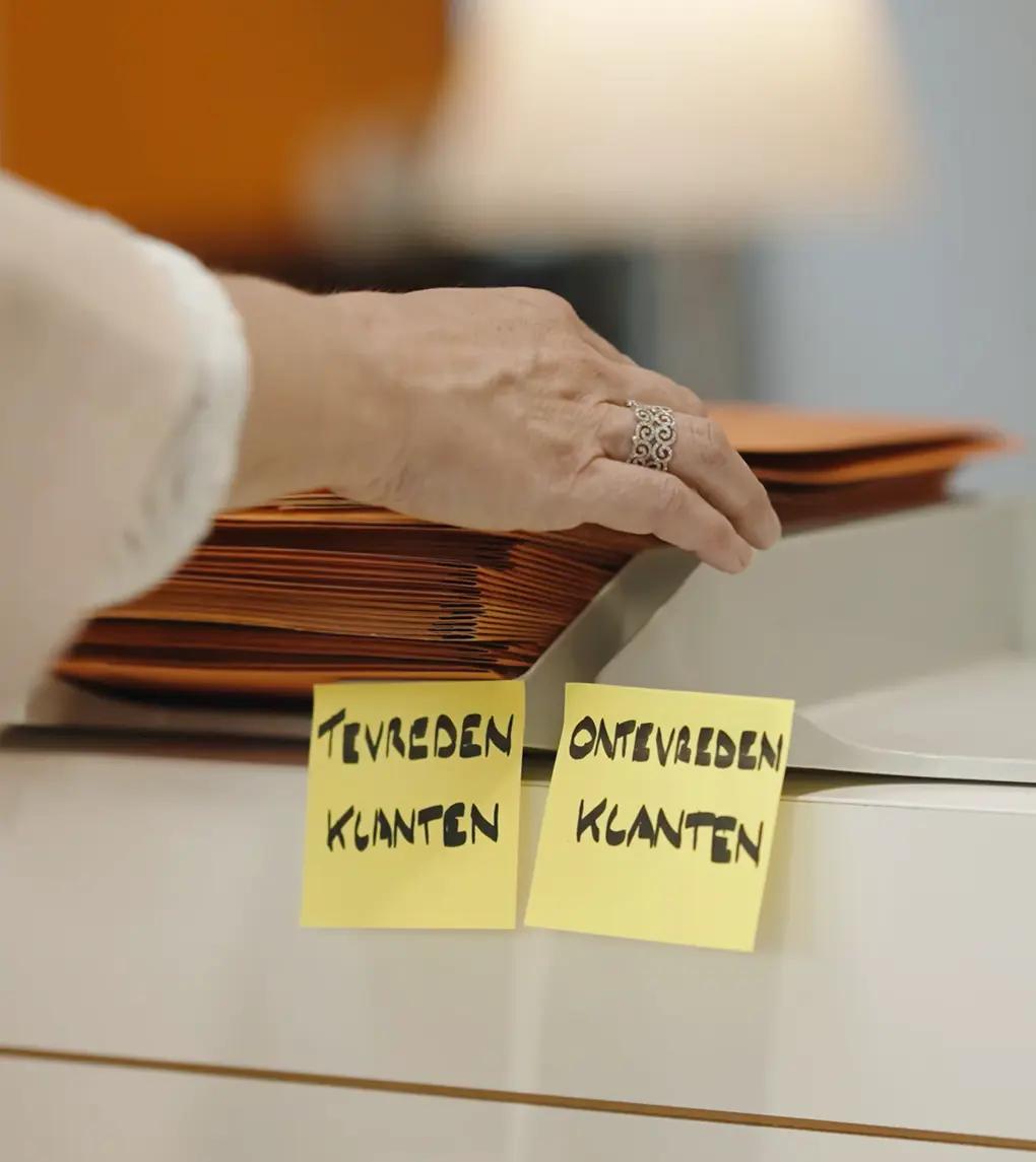 Stapel folders in bakje met tevreden klanten